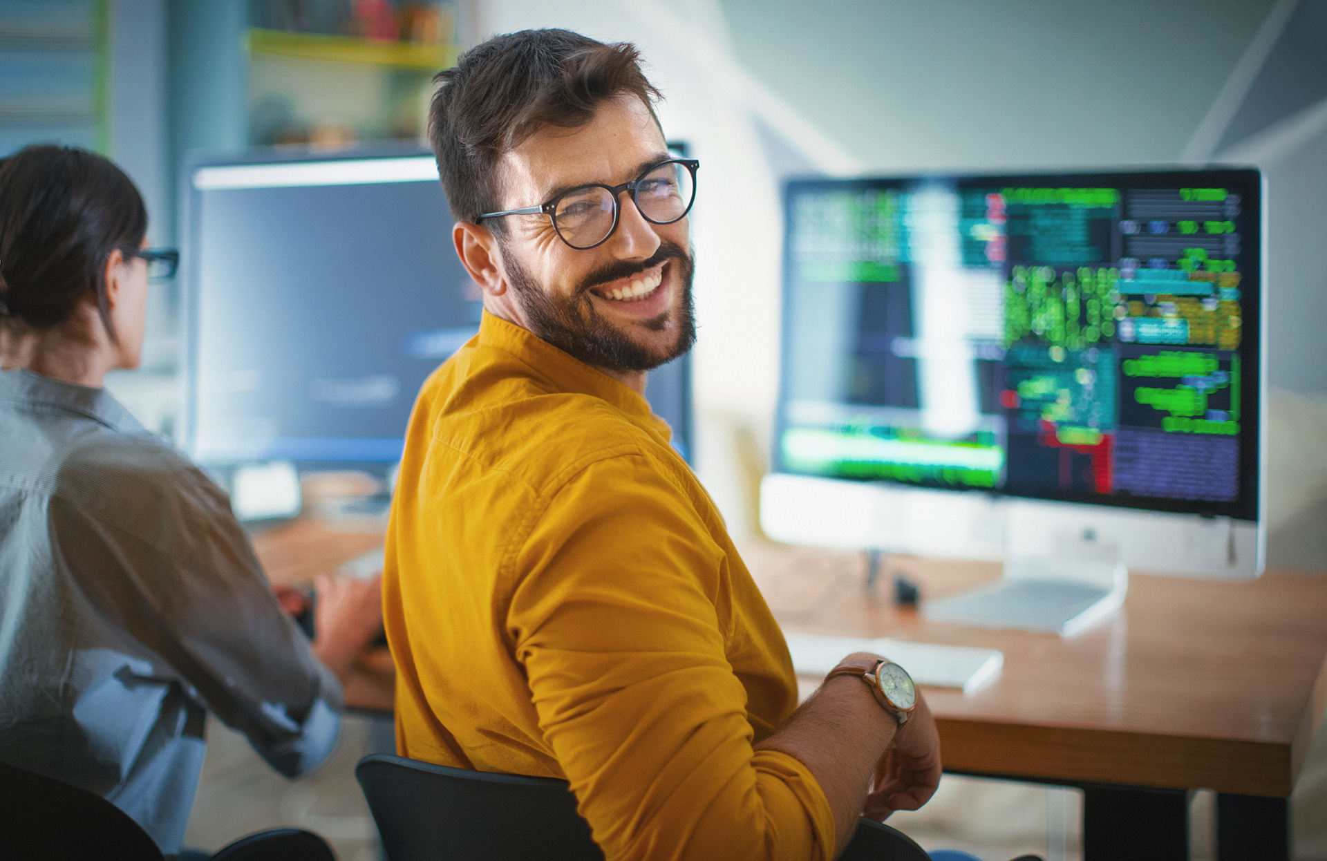 Software developer smiling at camera while working on code